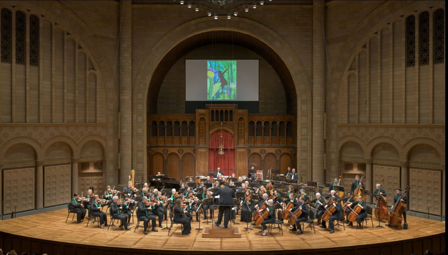 Orchestra performing with images drawn by child artists projected on screen above